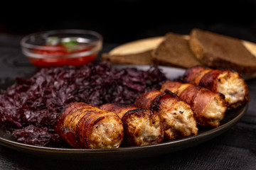 Fried homemade grilled sausages or chevapchichi with stewed sauerkraut, and slices of rye bread and tomato sauce on a wooden rustic background