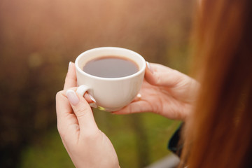 Closeup cup of coffee in hands of beautiful young woman