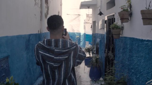 A tourist man taking pictures of a beautiful street in Chefchaouen city Morocco. exploring the blue city of Morocco
