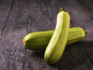 Two ripe zucchini on a black wooden table.