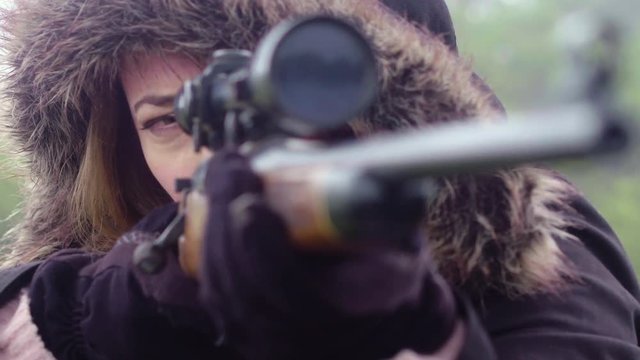 Close up of a female hunter holding a rifle and taking aim using the telescopic scope, 30 fps.