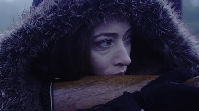 Close up side profile of a woman holding a weapon, focussed on her target at night, 23.98 fps.
