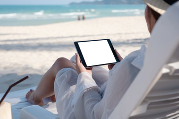 Mockup image of a woman holding a black tablet pc with blank desktop screen while laying down on...