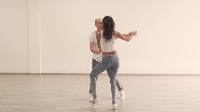 Young Beautiful Dancer With Long Curly Black Hair in High Heels Practicing Latin Dance Moves in Studio With Her Male Partner in Dance Studio