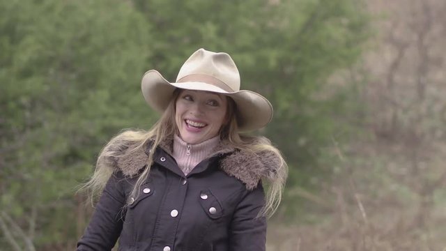 A laughing cowgirl having a great time, dressed up for winter out on the farm, 29.97 fps.