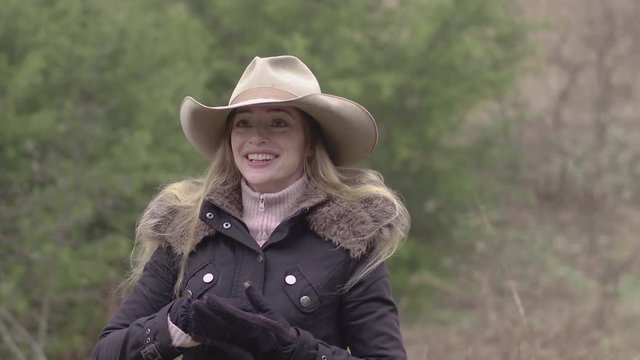 A very happy cowgirl with long hair, dressed up for winter out on the farm, 29.97 fps.