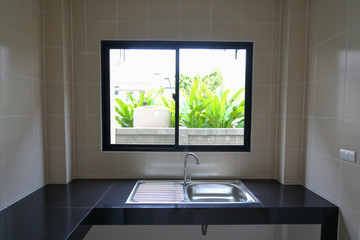 empty kitchen room cooking with stainless sink and built in black tile counter