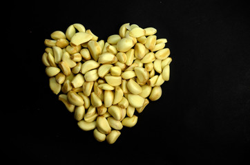 Group of garlic peeled in heart shapes on black background