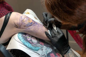 Tattoo master makes a client a colorful tattoo