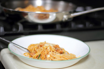 Pasta in a dish next a pan full of pasta.