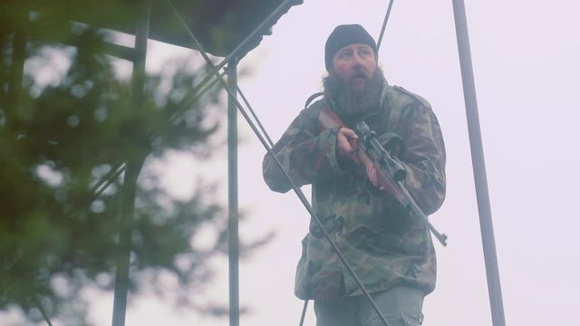 Grizzled hunter holding rifle, takes aim as prey comes into view