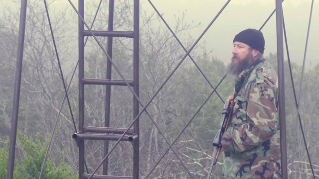 Gun nut standing guard in outpost tower for local militia, misty morning scene