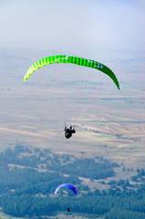 Two paraglider flying over the mountains during a paragliding competition