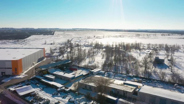 Drone flying near Kiev, large warehouse on the left side, winter landscape.