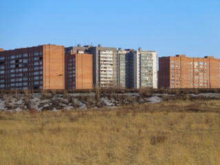 Apartment buildings on the outskirts of the city of Ust-Kamenogorsk (Kazakhstan). Multistory apartment buildings. Old and New. Yellow steppe. Spring. Blue sky