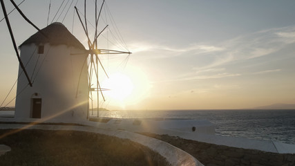 sunset shot of the windmills on mykonos greece with lens flare