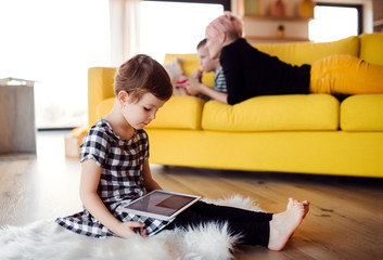 A small girl using tablet indoors on the floor at home.