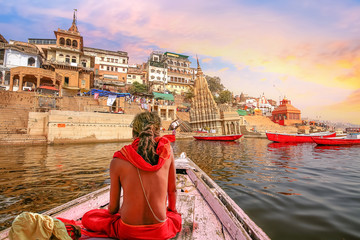 Varanasi city architecture with Ganges river bank at sunset with view of Hindu sadhu enjoying a...