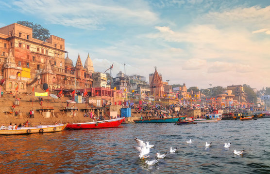 Varanasi Ganges river ghat with ancient city architecture with view of migratory birds on river Ganga at sunset.