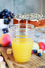 Orange juice glass among various fruits.