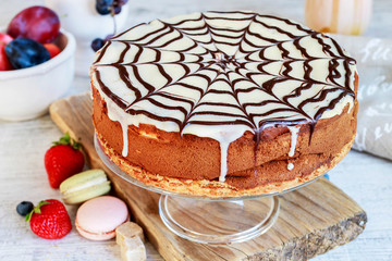 Halloween chocolate spider web cake and various fruits around.