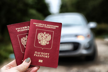 Russian passports in the hand of woman and car background