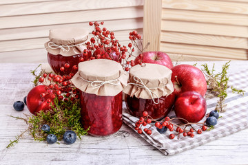 Glass jars with red jam. Autumn fruits around.