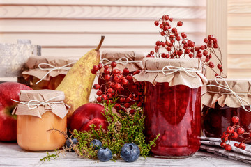 Glass jars with red jam. Autumn fruits around.