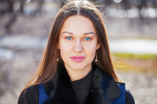 Portrait of a young beautiful woman in blue coat in spring park