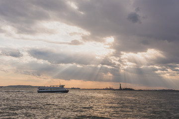 Boat traveling past Statue of Liberty at Sunset, in New York City, USA