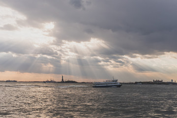 Obraz premium Boat traveling past Statue of Liberty at Sunset, in New York City, USA