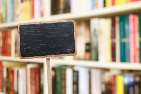 Blank blackboard label and blurred library in the background.