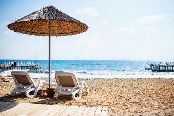 Sea sandy beach with the two deck chairs.