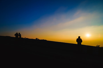 Fototapeta premium Silhouette of man on top of mountain, The silhouette of the photographer stands in the morning., Shadow tourists are watching the sunset on the mountain.