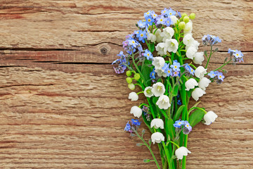 Bouquet of forget-me-not and lily of the valley flowers on wooden background