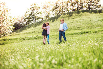 Fototapeta premium Senior couple with granddaughter outside in spring nature.