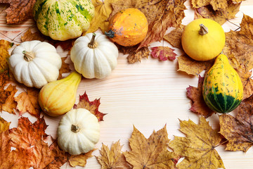 Pumpkins and colorful leaves on wooden background.