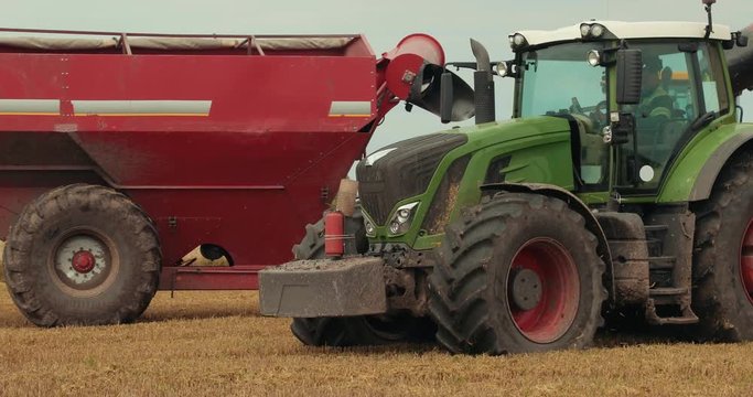 Green Tractor Rides Near The Yellow Tractor With A Red Trailer. Combine Working On The Field. Harvest. Barley Field. Agriculture. Prores, Slow Motion