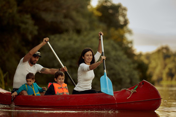 Family paddling red canoe in the river.
