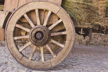 Wooden wagon with dry grass. Ancient cart with wooden wheels. Traditional rural transport. Historic rustic vehicle with dry hay. Woodem handmade wheels.  Travel concept. Agriculture concept.