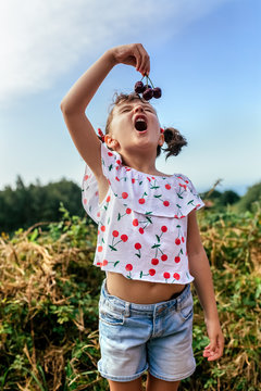 Expressive little girl eating cherries