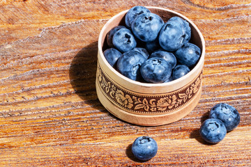 Russian birch tree bark bowl of fresh blueberries on rustic wooden table. Healthy organic seasonal fruit background. Organic food blueberries for healthy lifestyle.