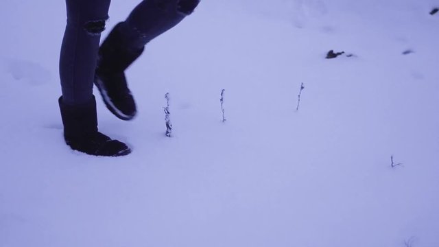 Woman wading through snowy medow in stylish teared jeans in ugg boots