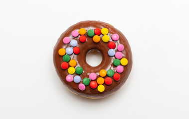 Chocolate donut with colorful decoration isolated on white background, top view
