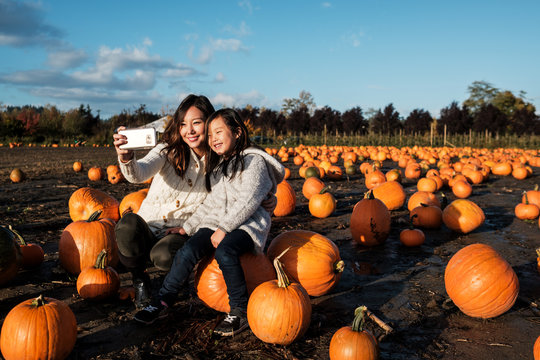 Asian Mother and Daughter Taking Selfie Picture During Pumpkin Patch