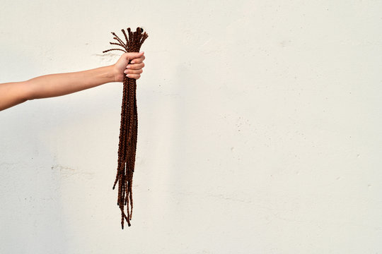 Woman's arm with cut hair over wall.