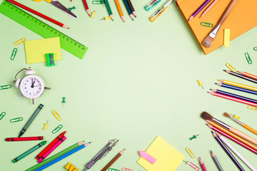 Flat lay frame composition from school supplies on a green background. The concept of the teacher's day.
