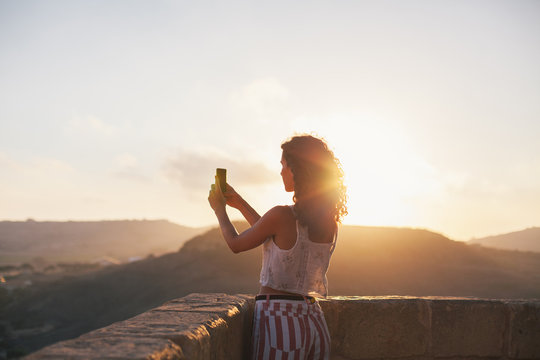 Attractive woman taking a picture during sunset
