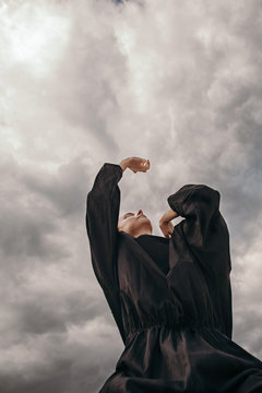 Person dancing under cloudy sky
