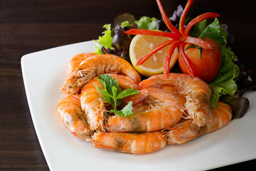 Baked Shrimp with salt and vegetables on white dish and dark brown background
